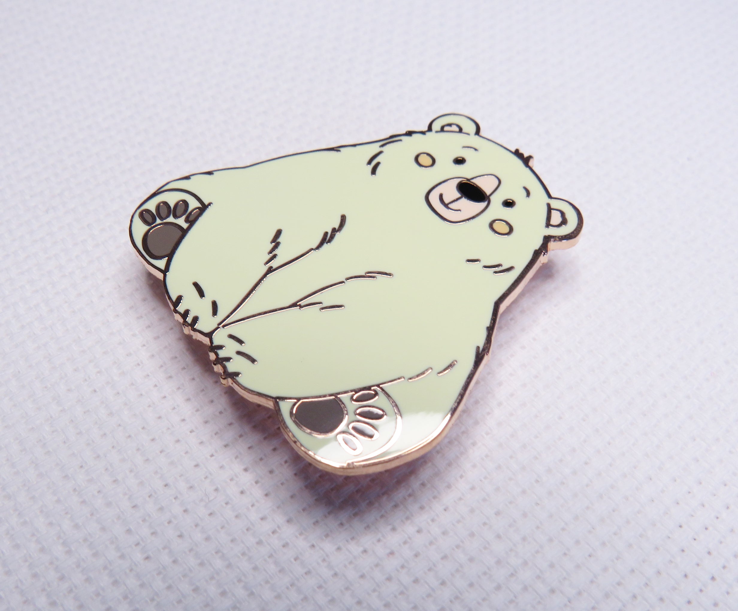 Light green bear-shaped pin on a textured white background