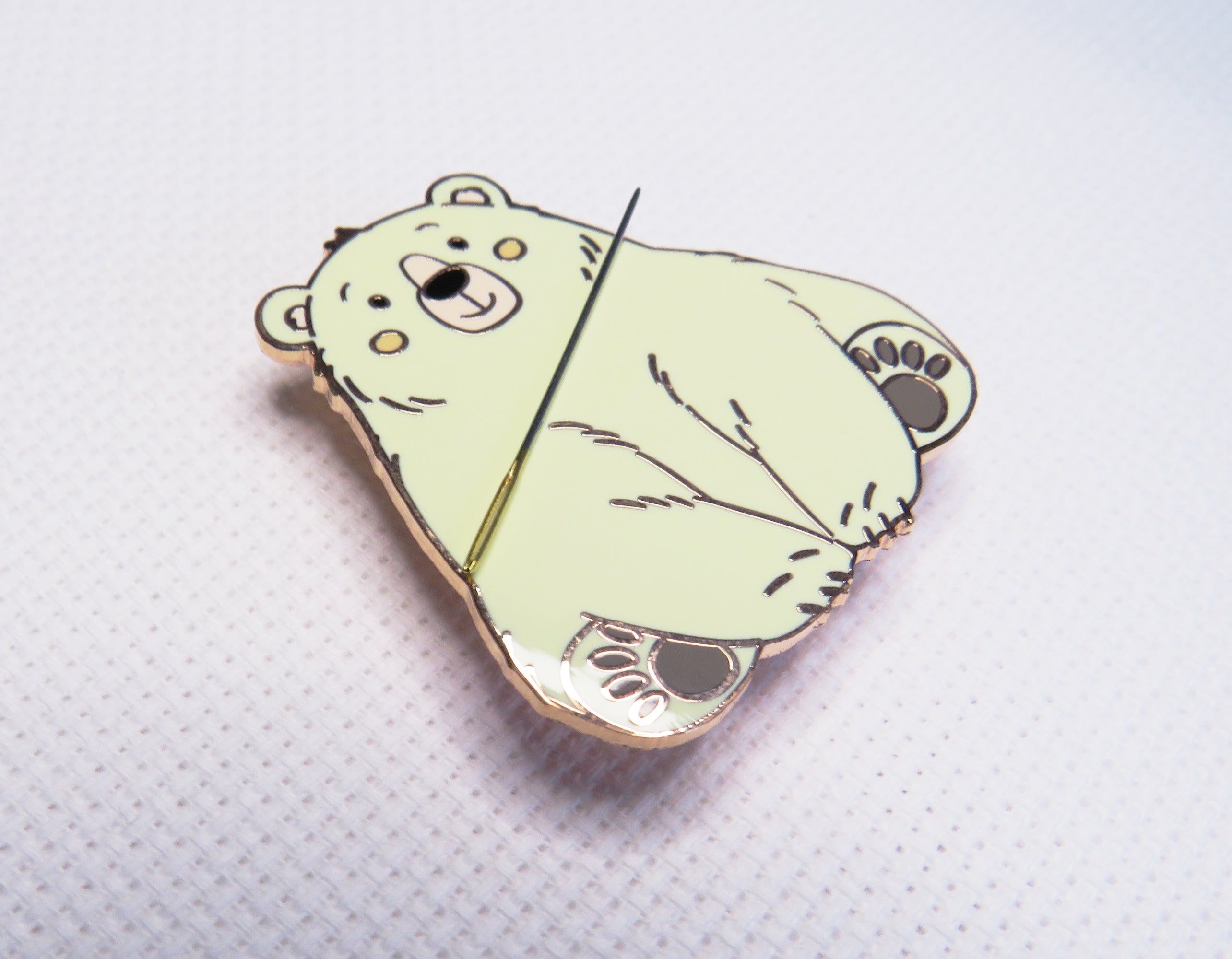 Light green bear-shaped pin on a textured white background