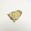 Beige seal-shaped pin on a white textured background