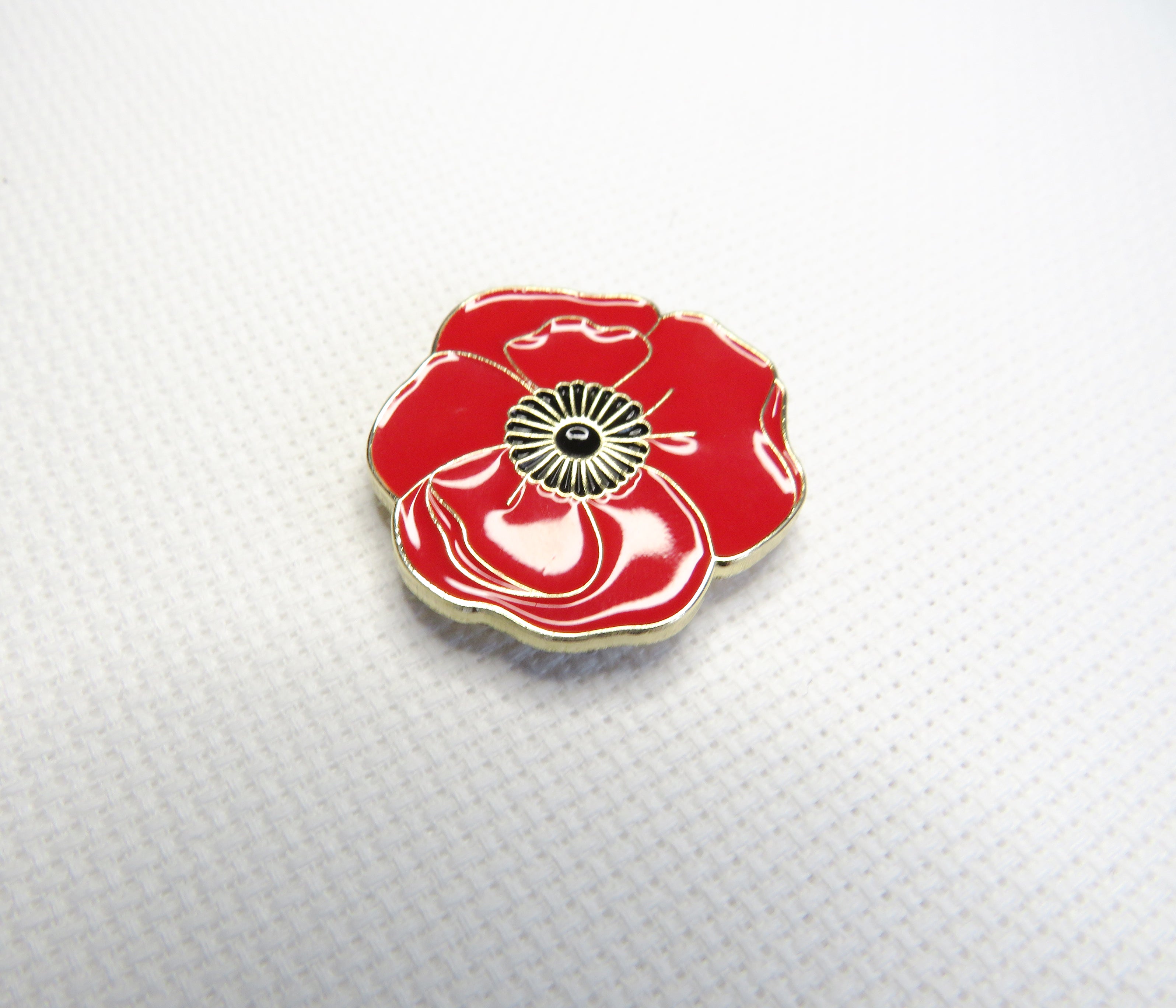 Red poppy flower needleminder on a textured white background
