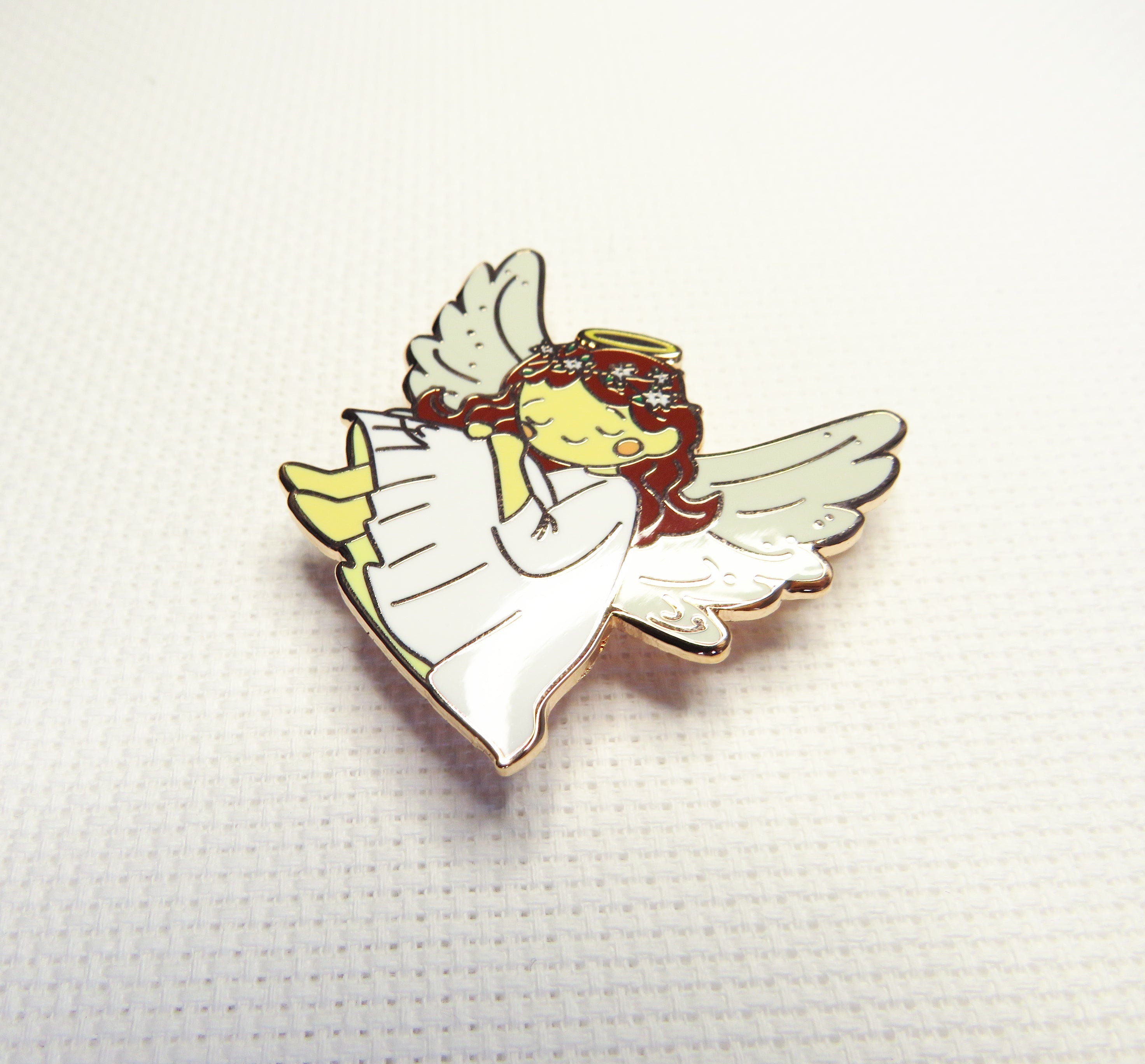 Angel-shaped needleminder on a textured white background