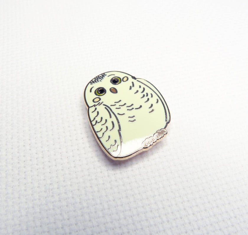 Enamel pin of a stylized owl on a textured  background