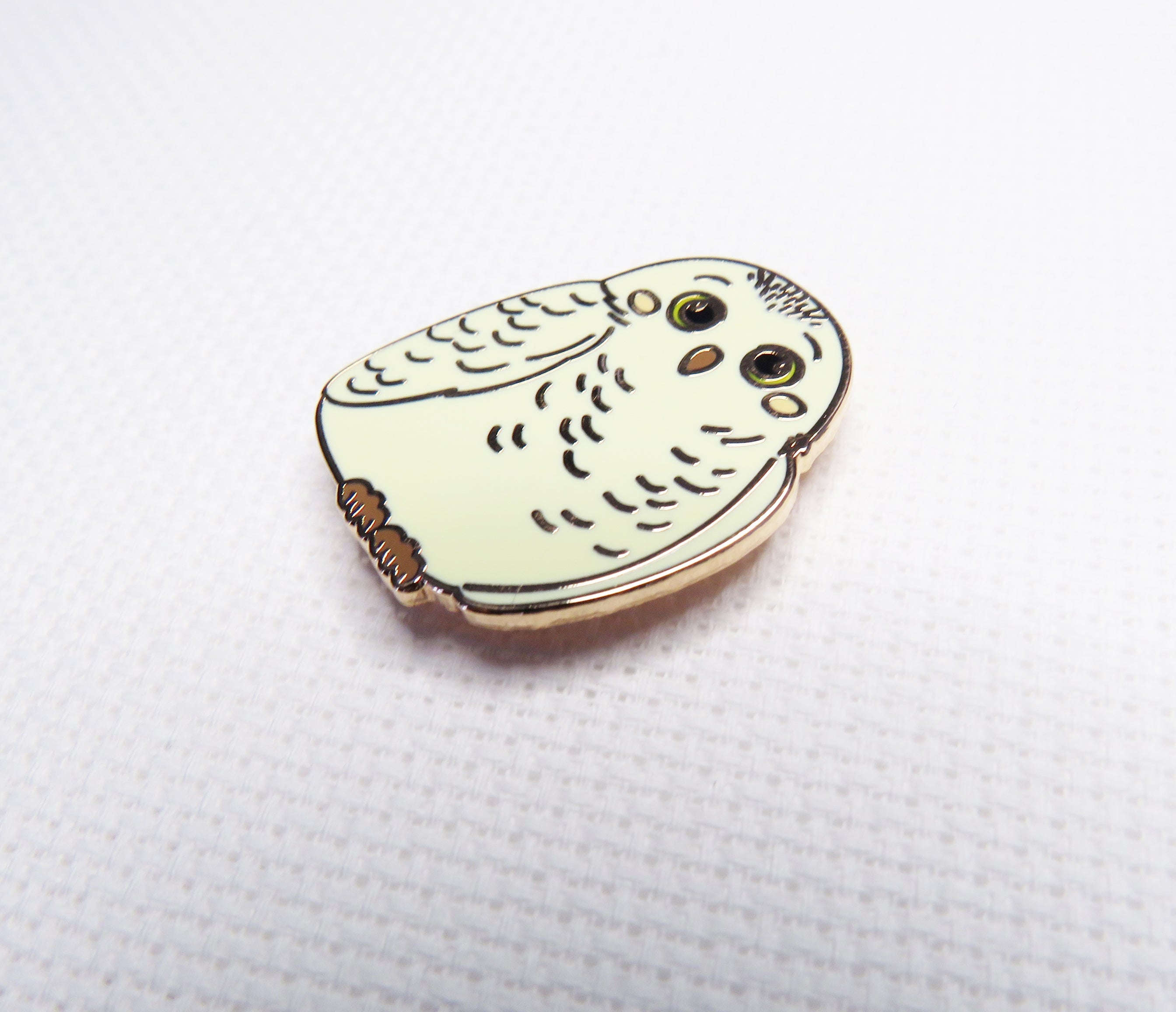 Owl-shaped pin on a white backgrounds