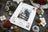 Lucas cross-stitch kit packaging with Christmas decorations on a dark surface