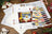 Cross stitch kit with color chart and pattern on a wooden table with Christmas decorations.