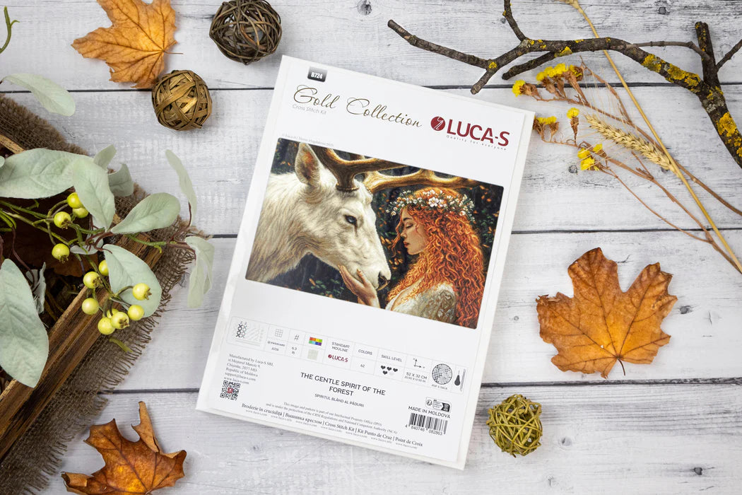 Lucas Gold Collection packaging with a deer and woman design on a wooden surface with fall leaves and branches.