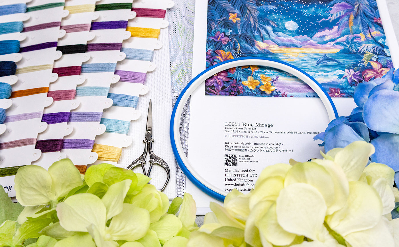 Embroidery hoop with floral design, scissors, and fabric swatches on a table.