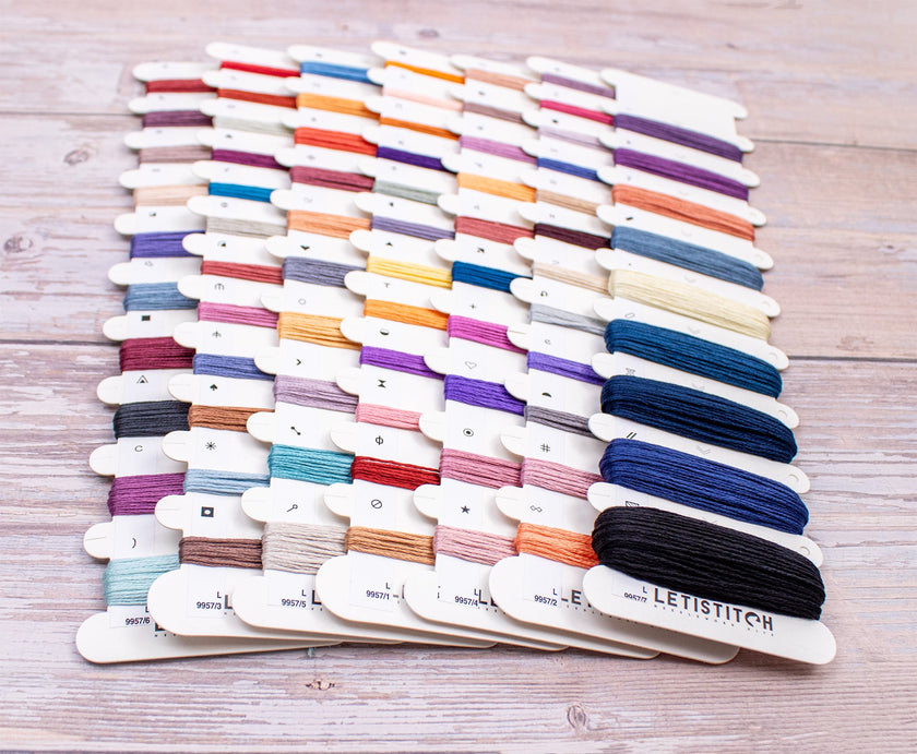 Assorted spools of thread on a wooden surface with 'Levitstitch' branding.