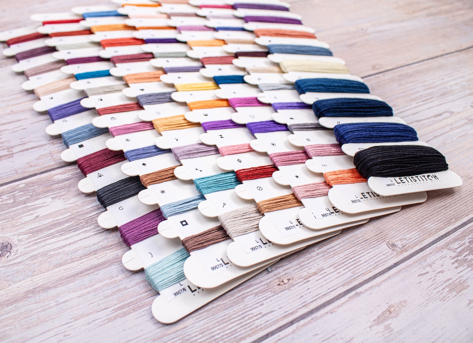 Assorted spools of thread in various colors on a wooden surface