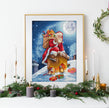 Framed artwork of Santa Claus on a sleigh with presents against a snowy night sky, displayed on a decorated Christmas mantel.