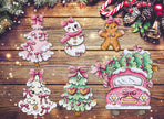 Cross-stitched Christmas-themed ornaments on a wooden surface with festive decorations.