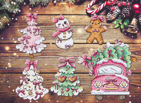 Cross-stitched Christmas-themed ornaments on a wooden surface with festive decorations.
