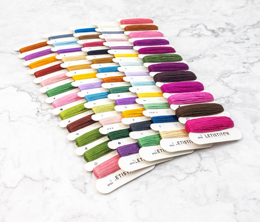 Set of colorful embroidery threads on a white marble surface