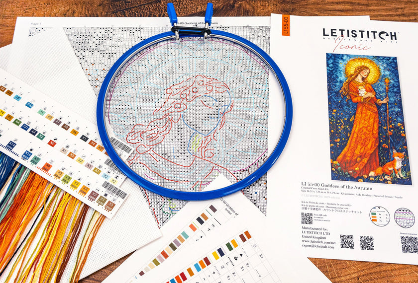 Embroidery hoop with cross-stitched design on a table with Letistitch embroidery kit and color swatches.