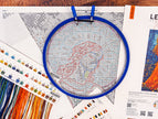 Cross-stitching project with an embroidery hoop and color chart on a wooden surface