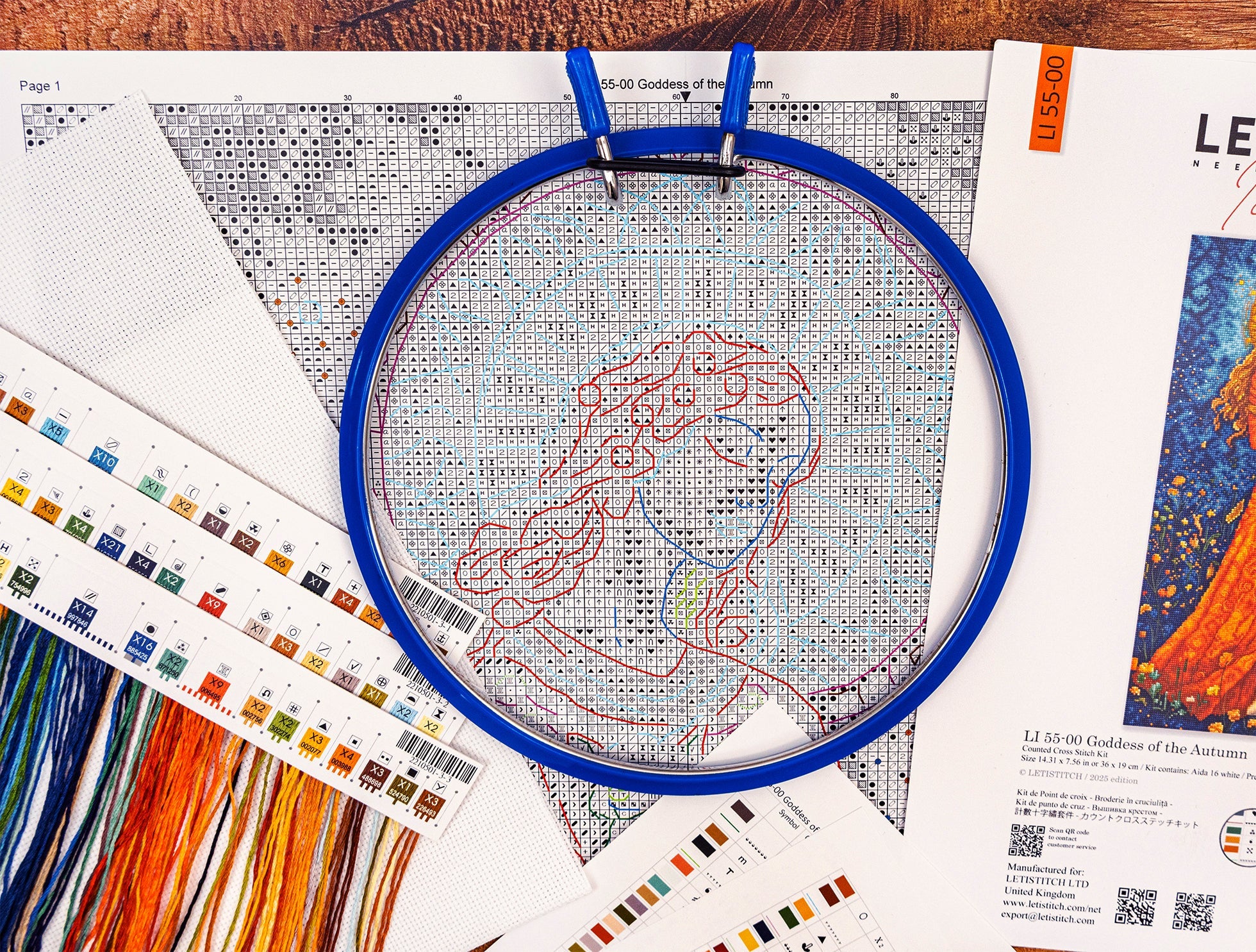 Cross-stitching project with an embroidery hoop and color chart on a wooden surface