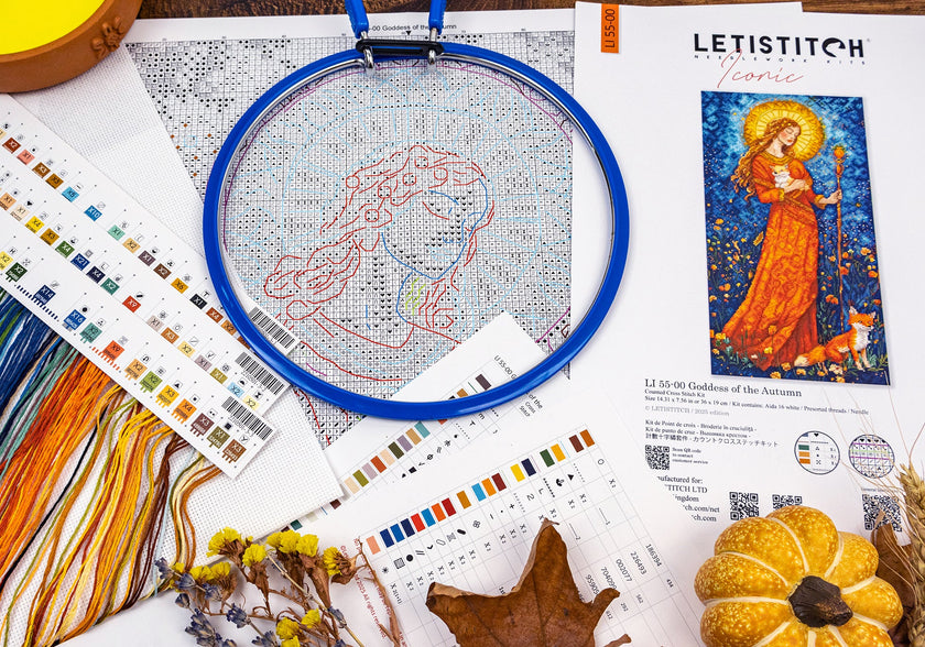 Cross-stitching hoop with fabric, threads, and pattern guide on a white surface