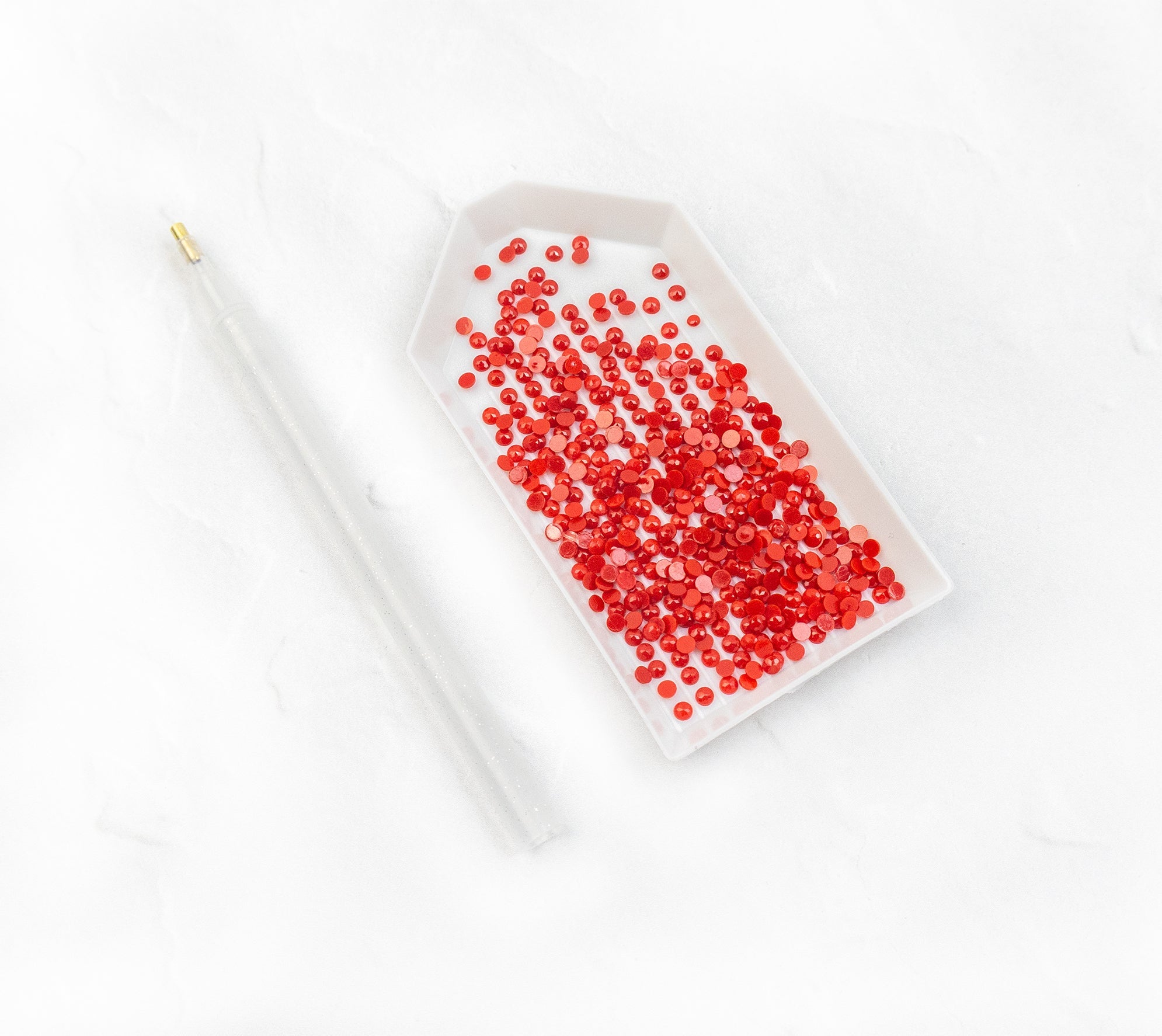 White dish filled with red beads on a white background