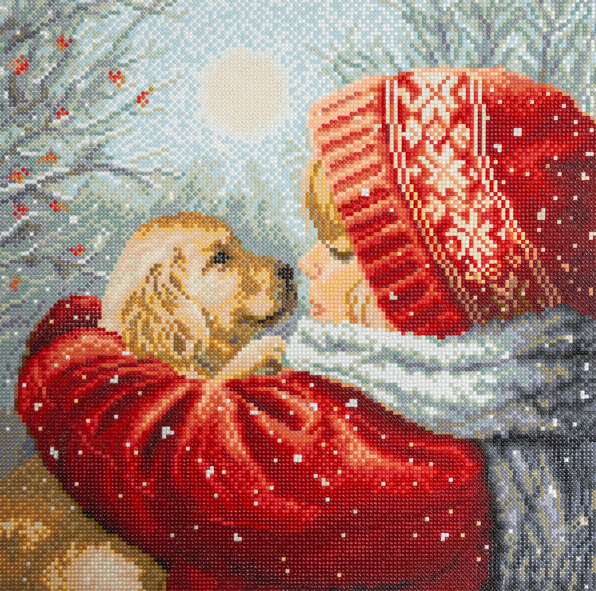 Cross-stitched scene of a child in a red coat and hat holding a dog, with a snowy background.