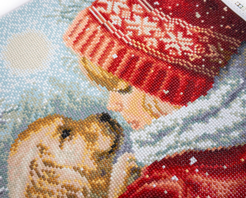 Close-up of a beaded artwork depicting two dogs in winter clothing with snowflakes in the background.