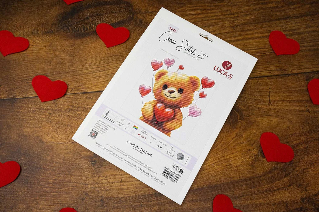 Cross-stitch kit for a teddy bear with hearts on a wooden surface