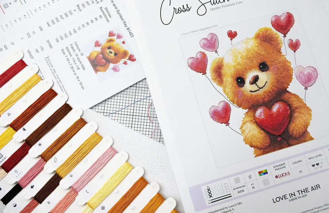 Cross stitch kit with a teddy bear design and color swatch on a white background