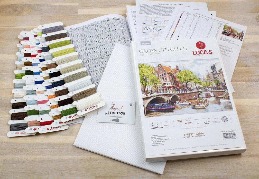 Cross stitch kit with threads, patterns, and a book on a wooden surface