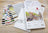 Cross stitch kit with threads, patterns, and a book on a wooden surface