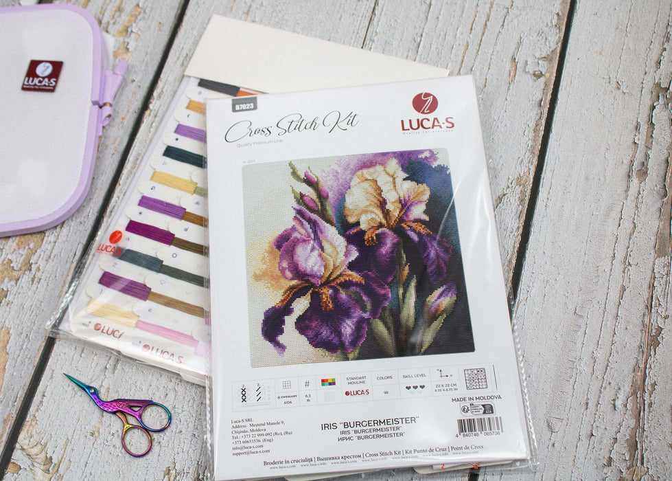 Lucas cross-stitch kit with fabric, threads, and scissors on a wooden surface