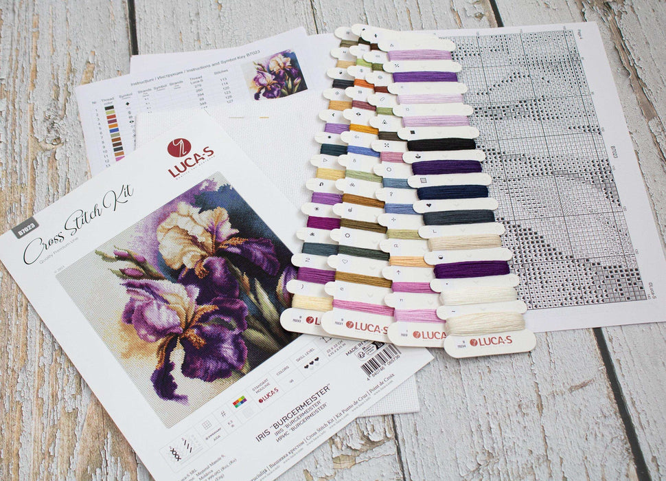 Cross stitch kit with fabric, thread, and pattern on a wooden surface