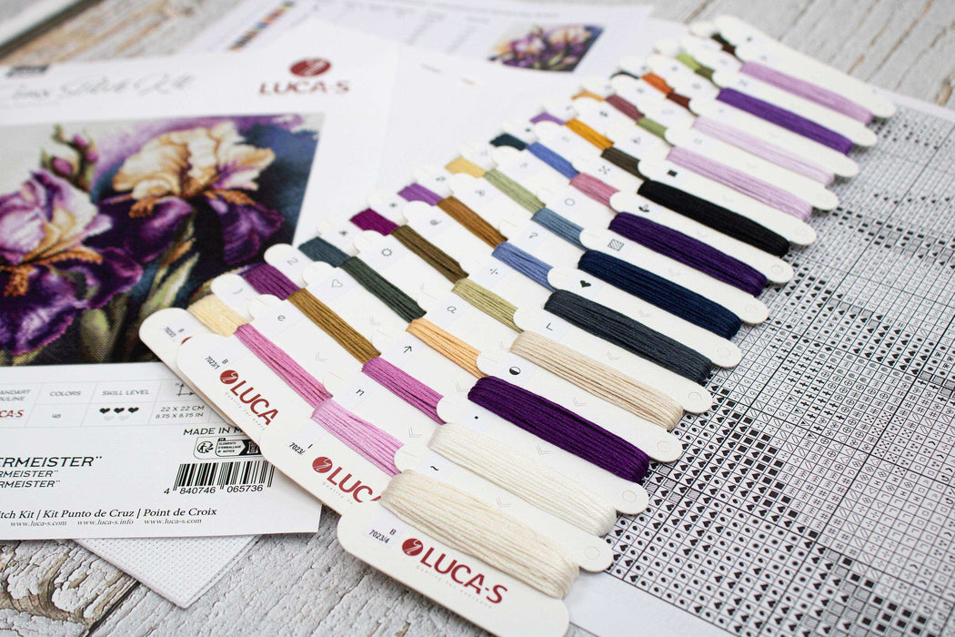 Color swatches and embroidery thread cards on a wooden surface with a floral pattern.
