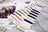 Color swatches and embroidery thread cards on a wooden surface with a floral pattern.