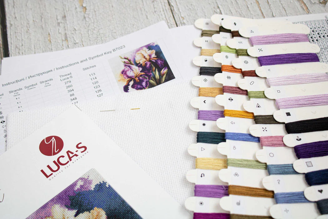 Color swatches and cross-stitch pattern on a wooden surface with Lucas brand visible.