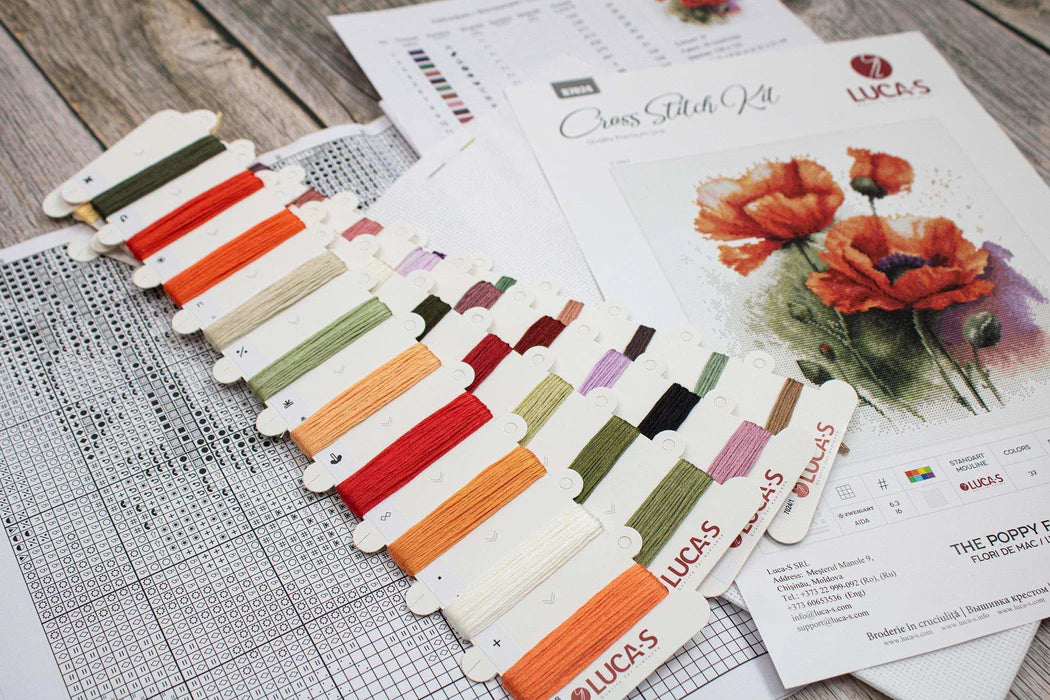 Set of Lucas embroidery threads on a wooden surface with patterned paper and fabric swatches.
