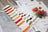 Set of Lucas embroidery threads on a wooden surface with patterned paper and fabric swatches.