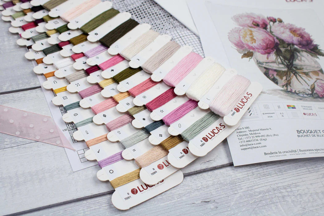 Color swatch cards with various yarn colors on a wooden surface, featuring the brand 'Lucas'.