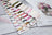 Color swatch cards with various yarn colors on a wooden surface, featuring the brand 'Lucas'.
