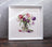 Framed artwork of a bouquet of tulips on a textured wall.