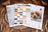 Cross stitch kit with thread colors and a dog illustration on a wooden surface with fall leaves.