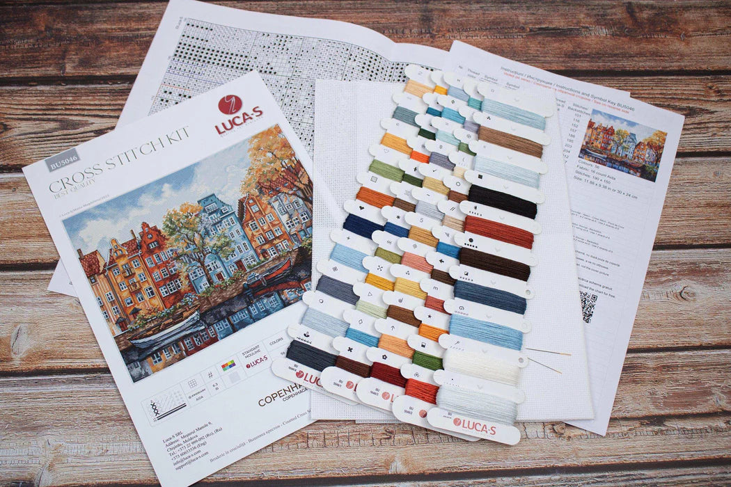 Cross stitch kit with color swatches and pattern on a wooden surface