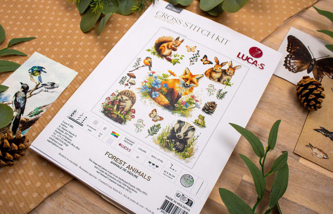 Lucas cross-stitch kit for forest animals on a wooden surface with decorative elements.