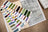 Collection of embroidery thread spools on a wooden surface with a patterned paper underneath.