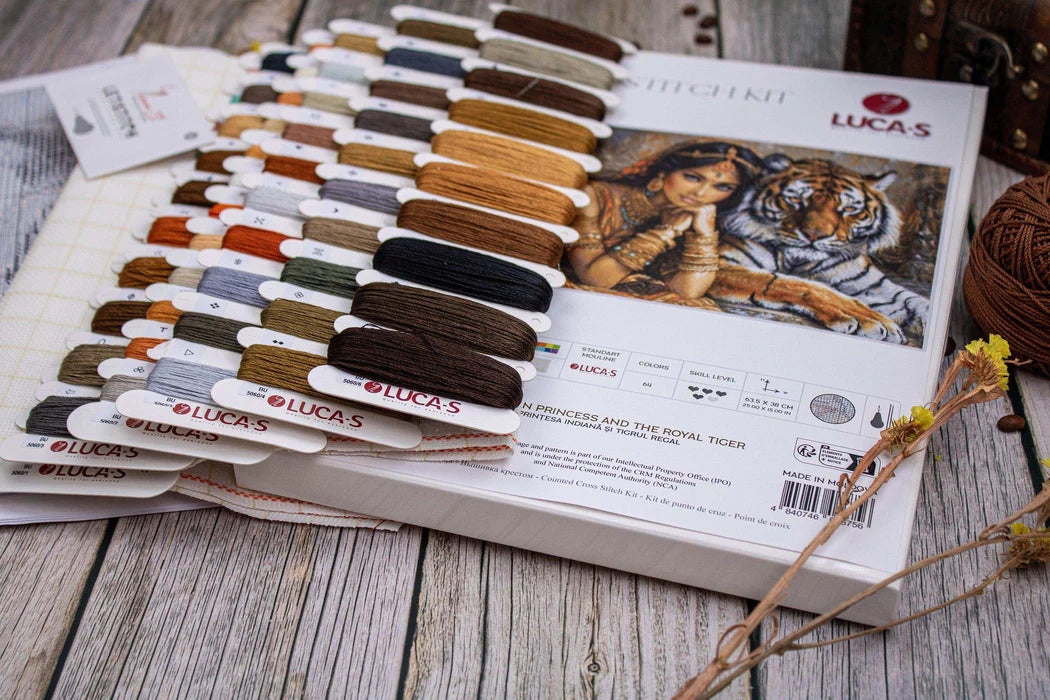 Lucas embroidery floss color chart with a tiger and woman illustration on a wooden surface.