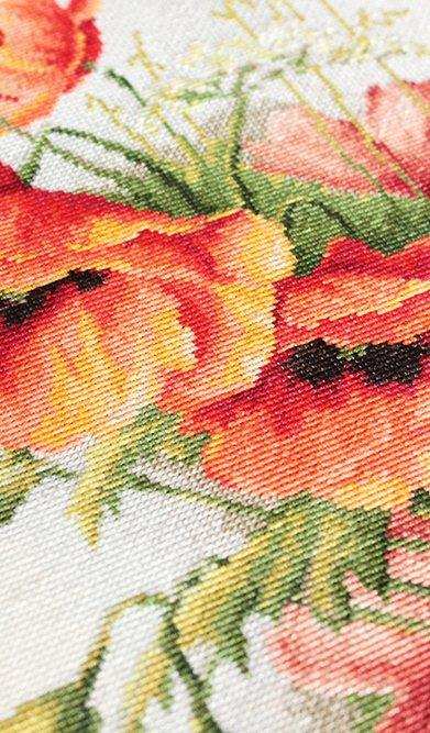 Close-up of a cross-stitched floral pattern with red, yellow, and green colors.