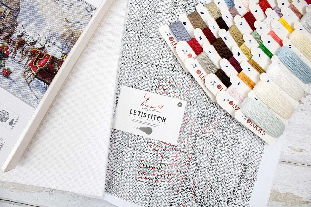 Collection of embroidery threads and a pattern book on a wooden surface