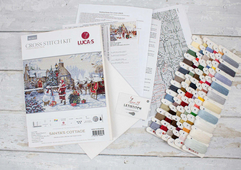 Cross stitch kit with pattern, threads, and instructions on a wooden surface