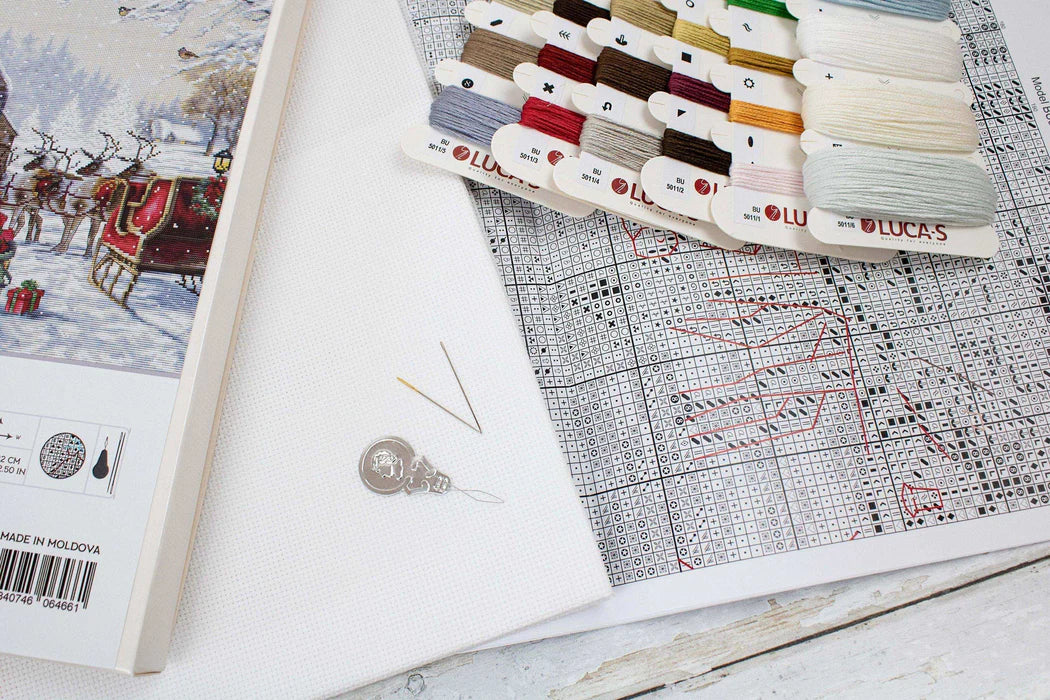 Thread spools and embroidery pattern on a wooden surface