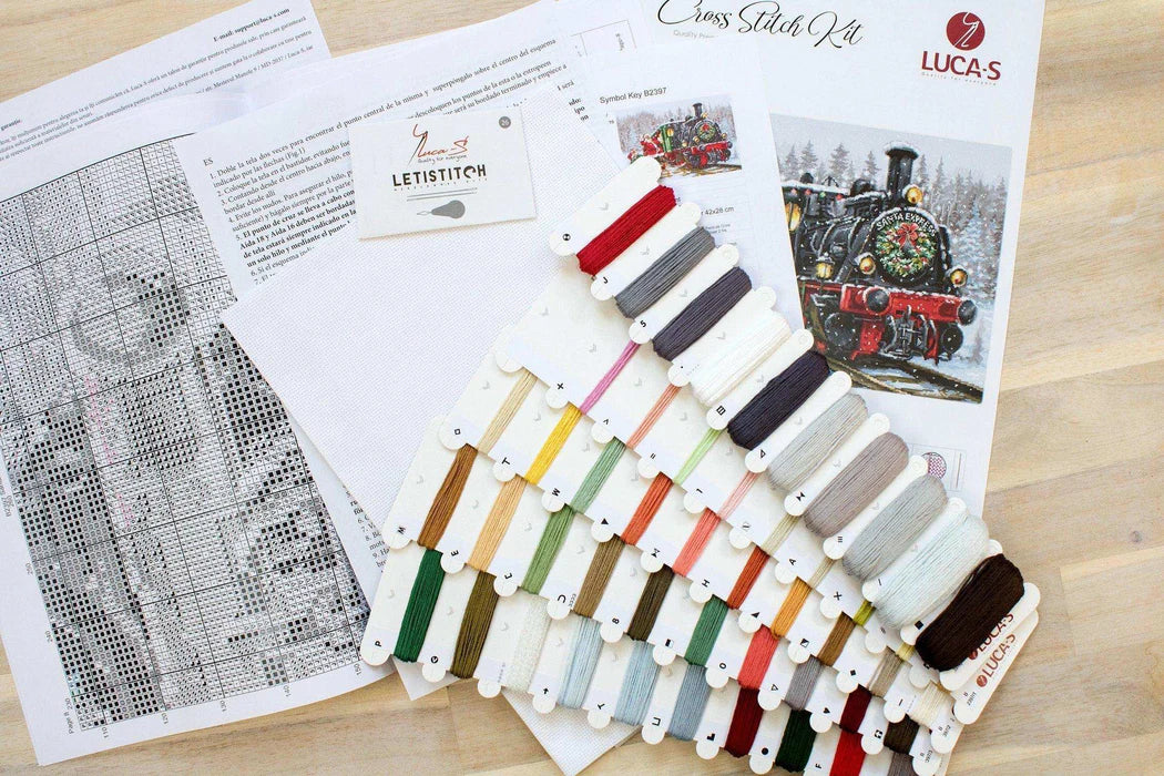 Cross stitch kit with thread samples and pattern on a wooden surface