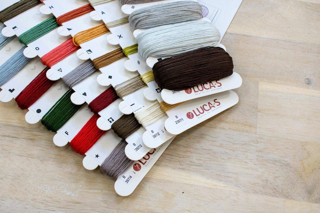 Set of embroidery threads on cards with 'Lucas' branding on a wooden surface