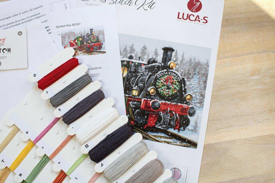 Cross stitch kit with color swatches and train design on a wooden surface
